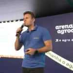 imagem mostra homem branco de meia-idade, com camiseta polo do Broto, no palco da Arena Agrodigital da Expodireto Cotrijal. Ele segura um microfone enquanto conversa com a plateia