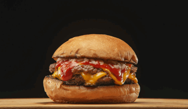 A imagem representa um hambúrguer feito com carne moída brasileira, afetada pelas tarifas norte-americanas, servido com queijo e pão artesanal